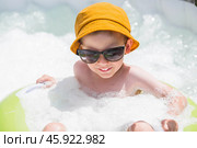 It's a hot day. A cute boy in sunglasses and a panama hat swims on a circle in a foam pool. The concept of summer holidays with children. Стоковое фото, фотограф Photojuli / Фотобанк Лори