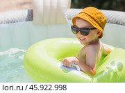 It's a hot day. A cute boy in sunglasses and a panama hat swims on a circle in a foam pool. The concept of summer holidays with children. Стоковое фото, фотограф Photojuli / Фотобанк Лори