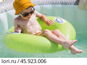 It's a hot day. A cute boy in sunglasses and a panama hat swims on a circle in a foam pool. The concept of summer holidays with children. Стоковое фото, фотограф Photojuli / Фотобанк Лори