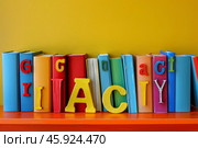 Colorful books on shelf with the word graciacy spelled out. Стоковое AI-изображение, AI-художник Иван Рябоконь / Фотобанк Лори