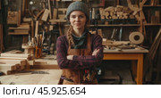 young woman experienced carpenter in leather apron standing in carpentry workshop and looking at camera. Стоковое AI-видео, аниматор Александр Довянский / Фотобанк Лори