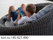 A 5-year-old little boy with a smartphone in his hands on the veranda. The child is playing on the phone. Harm of gadgets for children. Protect your child from the smartphone. Kids and gadgets. Стоковое фото, фотограф Photojuli / Фотобанк Лори