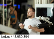 Bearded man in gym performs exercises for arm muscles using simulators and fitness center equipment. Стоковое фото, фотограф Яков Филимонов / Фотобанк Лори