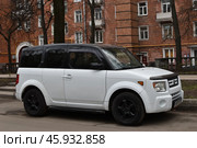 Белый с чёрной крышей автомобиль вместительный кроссовер Honda element припаркован у обочины во дворе кирпичного красного многоквартирного дома на ул. Куусинена в Москве весной (2024 год). Редакционное фото, фотограф Алиса Сокол / Фотобанк Лори