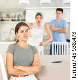 Offended young woman sitting at kitchen during argument with husband and mother-in-law. Стоковое фото, фотограф Яков Филимонов / Фотобанк Лори
