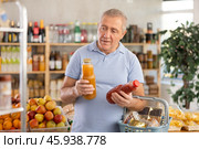 Mature man hold white plastic bottles and choose consider juice in store. Стоковое фото, фотограф Яков Филимонов / Фотобанк Лори