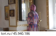 A woman stands in an Orthodox church and looks at a large icon: Belarus - 2021. Редакционное видео, видеограф Дмитрий Нечаев / Фотобанк Лори
