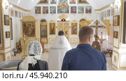 Man and woman stand with their backs behind the priest inside the Orthodox Church, Interior Orthodox Temple St. Nikita the Confessor: Belarus - 2021. Редакционное видео, видеограф Дмитрий Нечаев / Фотобанк Лори