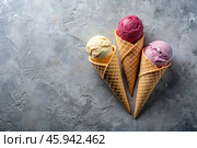 Sweet dessert. Ice cream cones with different flavors on a concrete gray background. World Ice Cream Day. Стоковое AI-изображение, AI-художник Photojuli / Фотобанк Лори