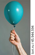 Hand holding blue balloon in gentle movement against gray background. Стоковое AI-видео, аниматор Zakharova Natasha / Фотобанк Лори