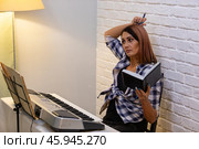 Beautiful woman in checkered shirt playing music synthesizer at home, composes music, learns musical scores. Стоковое фото, фотограф Ольга Яковенко / Фотобанк Лори