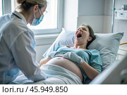 A pregnant woman in a hospital bed in the maternity ward. The woman is in labor and screaming in pain. Pregnancy and childbirth. Стоковое AI-изображение, AI-художник Photojuli / Фотобанк Лори