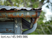 Rusty gutter and roof showing signs of neglect and disrepair. Стоковое AI-изображение, AI-художник Иван Рябоконь / Фотобанк Лори