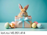 A holiday banner. A cute Easter bunny is peeking out of a gift box, and colorful eggs are scattered around. The concept of happy Easter. Стоковое AI-изображение, AI-художник Photojuli / Фотобанк Лори