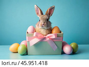 A holiday banner. A cute Easter bunny is peeking out of a gift box, and colorful eggs are scattered around. The concept of happy Easter. Стоковое AI-изображение, AI-художник Photojuli / Фотобанк Лори