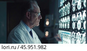 an elderly European male doctor in uniform studies an X-ray of the brain, a CT scan room, modern technologies, X-ray examination of the head. Стоковое AI-изображение, AI-художник Светлана Леуто / Фотобанк Лори