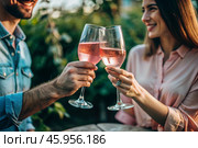 Glasses of pink sparkling wine in the hands of a couple in love. People on a romantic date. The concept of love. Стоковое AI-изображение, AI-художник Photojuli / Фотобанк Лори