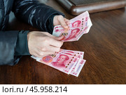 Мужчина пересчитывает деньги. Крупный план мужских рук с наличными юанями. Банкноты китайской валюты. Стоковое фото, фотограф Евгений Зимин / Фотобанк Лори