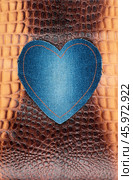 Blue denim heart lies on the brown crocodile skin. Стоковое фото, фотограф Александр Собко / Фотобанк Лори
