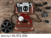 Retro camera in a brown leather case lies on a wooden table. Top view. Стоковое фото, фотограф Александр Собко / Фотобанк Лори
