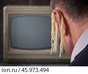 Человек перед телевизором с лапшой на ушах, концепция на тему обмана по телевидению, устойчивое выражение "вешать лапшу на уши", шаблон для дизайнера с копией пространства. Стоковое фото, фотограф Сергей Чайко / Фотобанк Лори