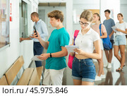 Teenage students checking exam schedule on bulletin board in college. Стоковое фото, фотограф Яков Филимонов / Фотобанк Лори