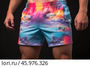 Bodybuilder wearing colorful shorts with galaxy print posing on black background. Стоковое AI-изображение, AI-художник Иван Рябоконь / Фотобанк Лори
