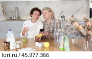 Two careful women scanning different products using their smartphones in the kitchen. Стоковое видео, видеограф Яков Филимонов / Фотобанк Лори
