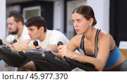 Focused girl works out with stationary bicycle during class at fitness club. Стоковое видео, видеограф Яков Филимонов / Фотобанк Лори