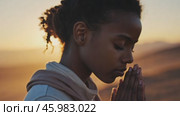 Young woman praying with closed eyes at sunset in desert. Стоковое AI-видео, аниматор Юрий Поздников / Фотобанк Лори