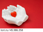 Stylish banner. In his hands, a red heart on a red background is made of plaster. World Health, Love and Insurance Day. World Heart, Health and Organ Donor Day. Стоковое фото, фотограф Photojuli / Фотобанк Лори