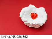 Stylish banner. In his hands, a red heart on a red background is made of plaster. World Health, Love and Insurance Day. World Heart, Health and Organ Donor Day. Стоковое фото, фотограф Photojuli / Фотобанк Лори