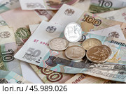 Блестящая монета номиналом один рубль ₽ на фоне бумажных  купюр разного достоинства. Крупный план. Выборочный фокус. Стоковое фото, фотограф Лариса Гордеева / Фотобанк Лори