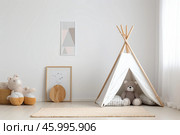 Cozy scandinavian interior design of playroom with teepee tent and teddy bear. Стоковое AI-изображение, AI-художник Иван Рябоконь / Фотобанк Лори