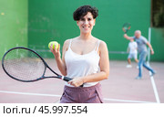 Smiling young Chilean woman with racket and balls on outdoor frontenis court. Стоковое фото, фотограф Яков Филимонов / Фотобанк Лори