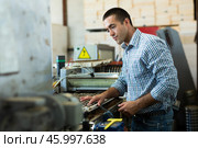 Farmer man working with automatic filling and seeding line for growing containerized seedlings of decorative plants in greenhouse. Стоковое фото, фотограф Яков Филимонов / Фотобанк Лори