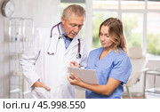 Mature man and middle-aged woman doctors together read new resolution, Стоковое фото, фотограф Яков Филимонов / Фотобанк Лори
