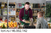 Seller in the apron offers a choice of packages of biscuits in the supermarket. Boy chooses delicious cookies. Buying desserts and confectionery for the family. Стоковое видео, видеограф Яков Филимонов / Фотобанк Лори