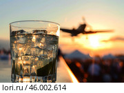 Refreshing gin and tonic enjoyed at sunset air show with plane taking off. Стоковое AI-изображение, AI-художник Иван Рябоконь / Фотобанк Лори