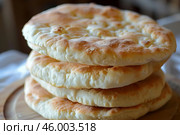 Stack of pita bread sitting on wooden cutting board. Стоковое AI-изображение, AI-художник Иван Рябоконь / Фотобанк Лори
