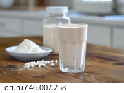 Protein shake, whey protein powder and casein protein on wooden table in kitchen. Стоковое AI-изображение, AI-художник Иван Рябоконь / Фотобанк Лори