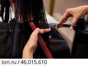 Hairdresser making fashionable hairstyle. Close-up hands of hairstylist combing and cutting wet hair of brunette lady in hair salon. Customer service at hair salon, haircare. Copy ad text space. Стоковое фото, фотограф Aleksandr Golubev / Фотобанк Лори