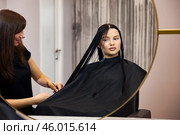 Brunette woman visit hairdresser, sitting on barber chair, looking at mirror. Hairstylist making fashionable hairstyle in barber shop. Customer service at hair salon, haircare. Copy ad text space. Стоковое фото, фотограф Aleksandr Golubev / Фотобанк Лори