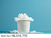White bucket overflowing with soap suds on blue background. Стоковое AI-изображение, AI-художник Иван Рябоконь / Фотобанк Лори