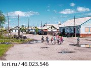 Сельская местность, дома, улица после дождя, дети на велосипедах, детские игры на улице. Поселок Томтор в Якутии ( Республика САХА, Оймяконский район ). Это очень удаленное место от Большой Земли, и жизнь здесь течет неторопливо (2010 год). Редакционное фото, фотограф Павел Просянов / Фотобанк Лори