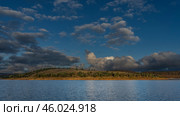 The golden hour of the evening. A calm lake with hilly shores. Green vegetation on the red soil of the hills. The clouds in the blue sky are highlighted. Madagascar. Mantasoa lake. Стоковое фото, фотограф Вера Ивановна Кубарева / Фотобанк Лори