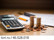 Coins stacked on wooden table with calculator and pen showing increasing profit. Стоковое AI-изображение, AI-художник Иван Рябоконь / Фотобанк Лори