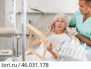 Male plastic surgeon giving professional advice after facial contouring to senior woman client looking at mirror. Стоковое фото, фотограф Яков Филимонов / Фотобанк Лори