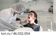 Girl doctor dentist in white coat examines oral cavity of male patient in dentistry. Стоковое видео, видеограф Яков Филимонов / Фотобанк Лори