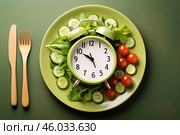 Green alarm clock on plate with salad, cucumbers and tomatoes symbolizing intermittent fasting and healthy eating habits. Стоковое AI-изображение, AI-художник Иван Рябоконь / Фотобанк Лори